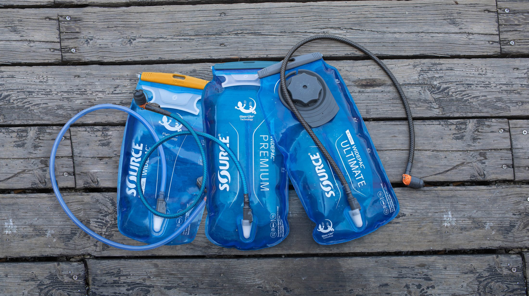 SOURCE Hydration Line — three hydration bladders on a wooden surface